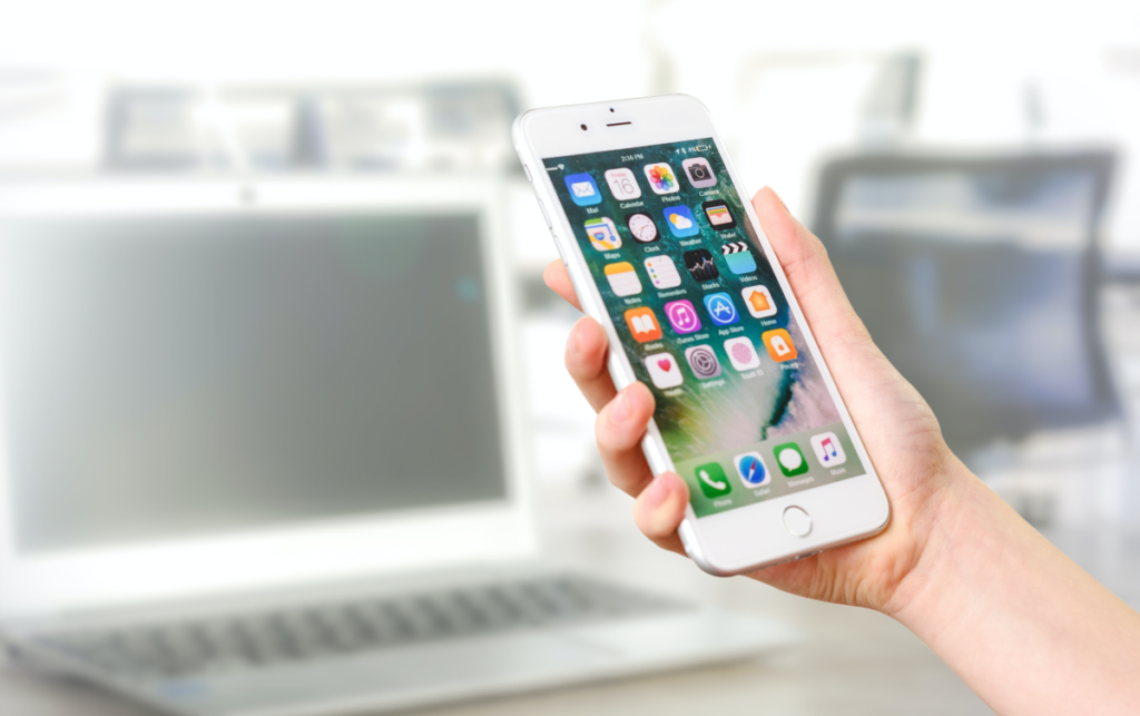 A hand holding a phone showcasing all social media icons.